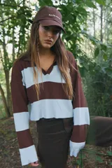 Buzo de punto estilo polo con diseño de rayas horizontales anchas en color marrón y celeste. Presenta cuello solapa, mangas largas y corte crop.