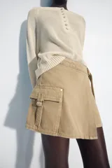 Falda pantalón cruzada de tiro medio en color tostado, con diseño estilo cargo que incluye bolsillos de parche con solapa y detalle de argolla metálica. Cuenta con trabillas y un cinturón integrado con hebilla metálica.