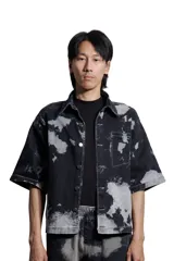 Camisa unisex de denim negro con estampado tie-dye en gris, corte boxy, manga corta y cuello clásico.