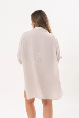 Vestido camisero beige de lino, con escote en V, cuello clásico, mangas tres cuartos regulables y cierre frontal de botones.