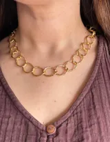 Collar corto de eslabones circulares texturizados en color dorado, elaborado en aluminio.