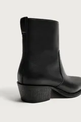 Bota de piel color negro con acabado abatanado, caña corta, punta fina y tacón cuadrado a tono.