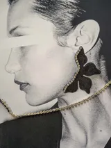 Par de aros dorados con forma de media flor, con detalle de strass negro y gancho de acero quirúrgico.