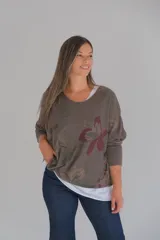 Sweater de corte amplio con diseño de doble capa, que presenta una capa superior en tono chocolate con estampado floral y una capa inferior en color blanco. Posee escote en V y mangas largas con terminaciones desflecadas.