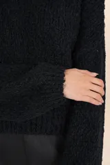 Suéter negro de tejido suave y esponjoso, con cuello redondo y mangas amplias de volumen.