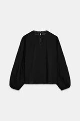 Camisa negra de manga larga con cuello redondo. Presenta detalles de entredós y jaretas verticales en el delantero, y cierre de botones en la espalda.