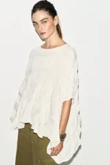 Top de cuello redondo color celeste con textura fruncida, mangas tipo capa y bajo asimétrico.