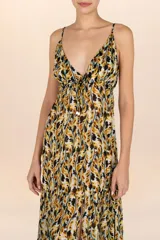 Vestido largo con estampado de hojas en tonos ocre, negro y blanco. Presenta escote en V profundo con ajuste de cordón bajo el busto, tirantes delgados ajustables y abertura frontal en la falda.
