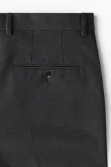 Pantalón sastrero gris oscuro con corte slim fit, pliegues frontales y raya marcada en las piernas. Cuenta con cierre de botón y bolsillos laterales.
