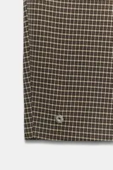 Pantalón de tiro medio con estampado de cuadros pequeños, bolsillos laterales y cierre frontal con cremallera y gancho metálico.