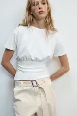 Camiseta blanca de algodón con cuello redondo, manga corta y diseño ajustado en la cintura tipo corset.