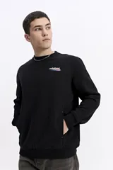 Buzo de algodón color negro, con cuello redondo, mangas largas con puños elásticos y bolsillos laterales. Presenta un pequeño logo estampado en el pecho.