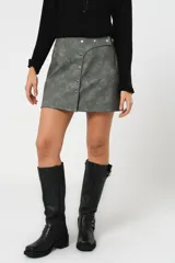 Minifalda gris con textura símil cuero, corte irregular con sobrefalda y cierre frontal con broches metálicos.