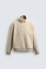 Sudadera de corte relajado confeccionada en tejido con textura de borreguillo, con cuello subido y cierre frontal de botones a presión. Presenta puños y ruedo con acabado en rib.