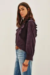 Camisa blanca de algodón con diseño romántico, cuello alto con volados, cierre frontal de botones y detalles de encaje y bordados calados. Presenta mangas largas con puños de encaje y volados frontales.