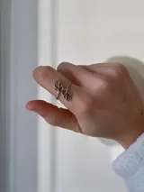 Anillo abierto de acero quirúrgico con diseño de dos hojas caladas enfrentadas.