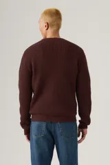 Sweater de punto con textura waffle, cuello redondo y mangas largas. Presenta un pequeño parche con logo en el puño izquierdo.