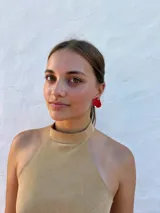 Aros tipo caravanas con diseño de flor irregular en color rojo vibrante y centro con detalle de pequeñas perlas.