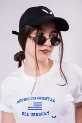 Remera blanca de algodón con cuello redondo y mangas cortas. Presenta un estampado frontal en color azul con la inscripción 'República Oriental del Uruguay' y la bandera nacional.