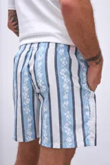 Short de baño celeste con rayas verticales blancas y estampado de flores blancas y azules.