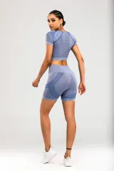 Conjunto deportivo azul con remera crop top de manga corta y calzas cortas.