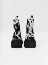 Bota tipo chelsea de cuero vacuno en color rojo con estampado floral grabado en negro. Presenta paneles laterales elásticos, suela de plataforma y taco cuadrado en color negro.