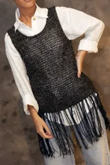 Top tejido de punto sin mangas, con diseño de red en color negro con destellos brillantes y flecos largos en el ruedo.