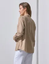 Camisa color verde oliva de lyocell, marca Cyrus. Tiene cuello con solapa, abertura central con botones, mangas 3/4 regulables con presilla y botón, y dos bolsillos delanteros aplicados.