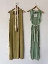 Vestido largo sin mangas color rosado, con escote redondo, bolsillos laterales y detalles de pasamanería en zigzag beige en el cinturón y los tajos laterales.