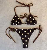 Conjunto de bikini con estampado de lunares, compuesto por un top triangular con tiras regulables y un short de baño ajustado a juego.