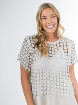 Blusa italiana calada con diseño floral en tono champagne, de mangas cortas y calce oversized.