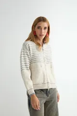 Campera tejida de punto con cierre frontal, diseño a rayas horizontales en la parte superior y bolsillos frontales tipo parche. Presenta puños y ruedo acanalados.