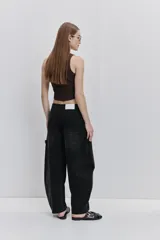 Jean negro de silueta barrel, tiro medio y pierna amplia que se curva hacia el ruedo. Cuenta con bolsillos delanteros y detalle de costuras decorativas.