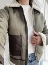 Chaqueta gamulan color verde con interior de piel sintética blanca, cierre frontal con cremallera y detalles en cuero marrón.