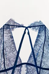 Body semitransparente de encaje azul marino con cuello halter, hombros descubiertos y tiras cruzadas en la espalda.