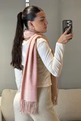 Bufanda rectangular de tejido suave con diseño de patrón escocés en tonos rosado y blanco, terminada con flecos en los extremos.