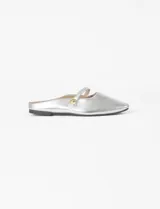 Mule tipo balerina color plateado, con punta fina y una tira decorativa sobre el empeine con un detalle de botón metálico dorado.