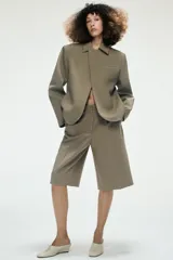 Bermudas de tiro alto con diseño de pinzas en el delantero, bolsillos laterales y cierre frontal con cremallera y gancho metálico.