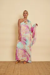 Vestido largo con diseño marmolado en tonos celestes, rosados y amarillos, de corte asimétrico con un solo hombro y manga larga acampanada.