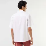 Camisa de manga corta de lino color blanco, con cuello camisero y cierre frontal de botones.