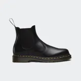 Botas Chelsea Dr. Martens modelo 2976, confeccionadas en cuero liso negro con acabado brillante. Presentan paneles elásticos laterales, tirador en el talón y la característica suela con amortiguación de aire y costuras amarillas visibles.