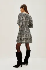 Vestido corto de algodón con estampado tipo mosaico en tonos blanco, negro y gris. Presenta escote en V profundo, mangas tres cuartos y falda con volado en el ruedo.