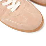 Zapatillas urbanas color nude, de cuero sintético, con cordones blancos y suela marrón.