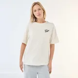 Camiseta de corte oversize color blanco crudo, con cuello redondo y mangas cortas. Presenta un pequeño estampado tipográfico en el pecho con la frase 'East Side League'.