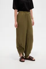 Pantalón verde militar de corte ancho y tiro alto, con cintura elástica fruncida y detalles de cordones ajustables en los tobillos.