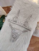 Conjunto de lencería compuesto por un bralette triangular de encaje con breteles regulables y una tanga a juego con laterales ajustables.