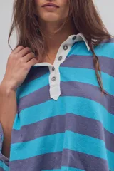 Remera tipo polo de algodón, de calce oversize, con diseño a rayas en tonos azul y celeste, cuello clásico blanco, botonadura corta, hombros caídos y mangas cortas.