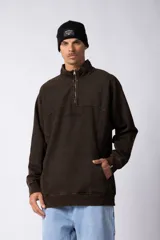 Buzo oversize de frisa con efecto de lavado gastado, color marrón. Presenta cuello alto con medio cierre frontal, bolsillo tipo canguro y bordado al tono en el pecho.