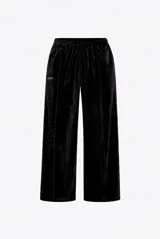 Pantalón de corte amplio y relajado confeccionado en terciopelo negro. Presenta cintura elástica, bolsillos laterales y botamanga recta, con un pequeño logo bordado en la parte superior.