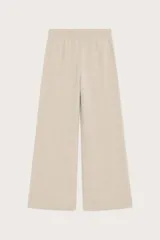 Pantalón de punto color beige, de corte recto y holgado, con cintura elástica y cordón ajustable. Presenta costuras verticales decorativas en el frente.